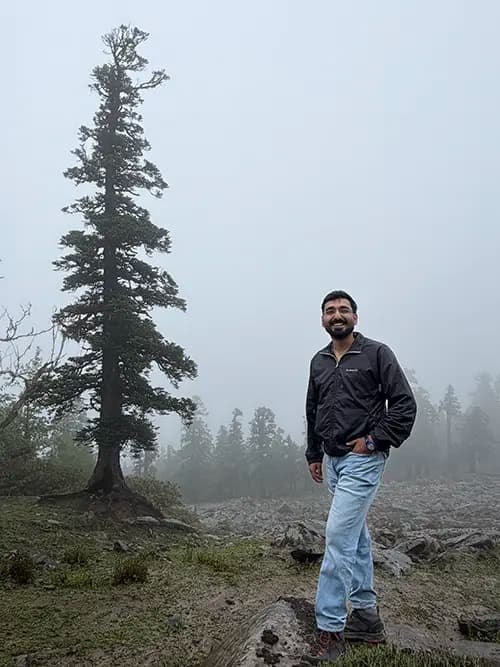 Dr. Yashasvi Verma standing outdoors beside a tall tree